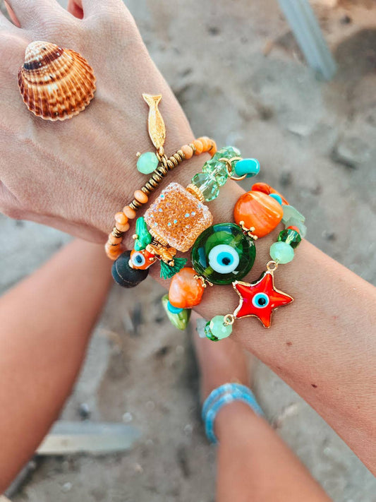 Sommararmband i orange och grön med öga i den gröna pärlan.